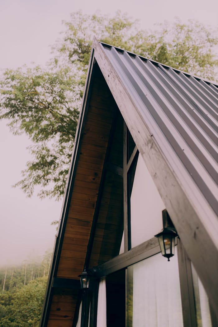 Home A scenic A-frame cabin blending with the serene forest backdrop under a calm day sky.